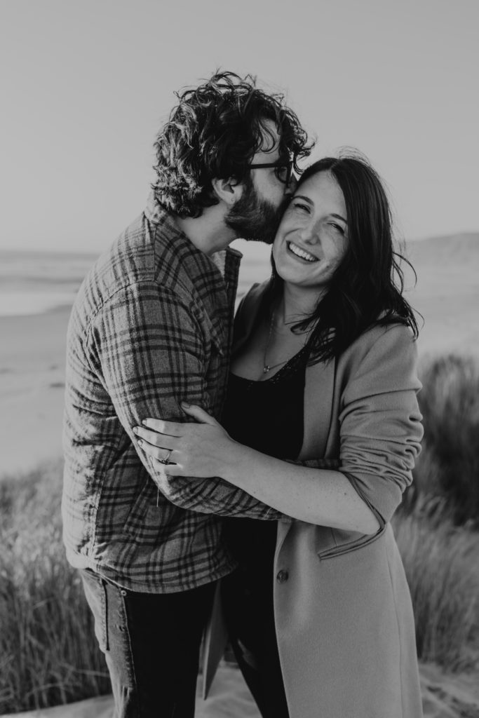 couple hugging on beach during beach engagement