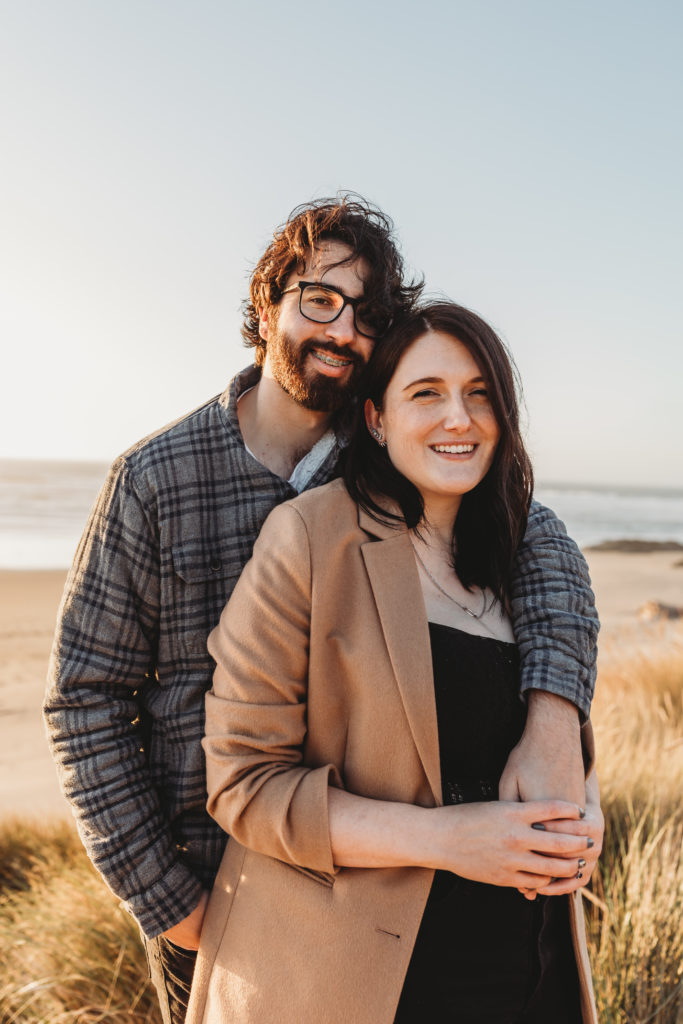 couple hugging on beach during beach engagement