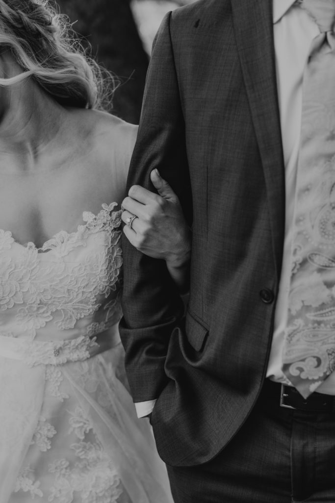 bride holding grooms arms showing off wedding rings