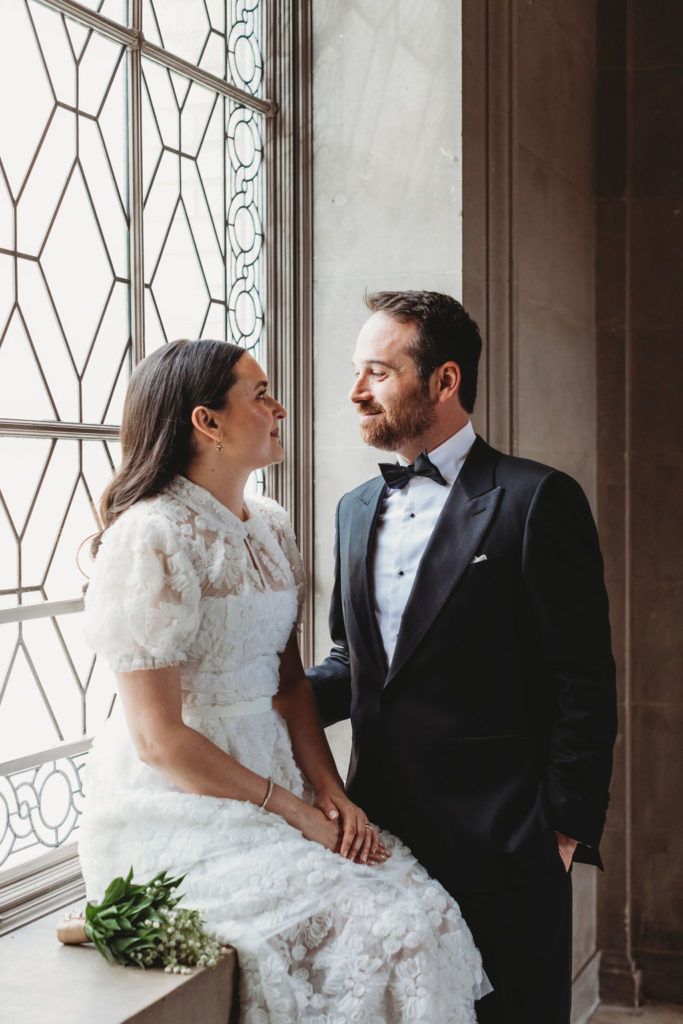 Newly wed couple posing by city hall windows after San Francisco City Hall wedding