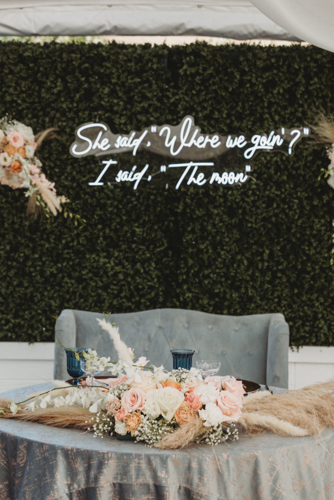 bride and grooms table with neon sign