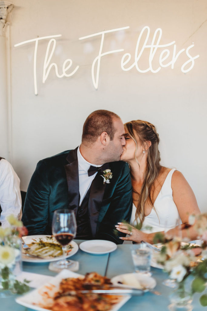 photo of bride ad groom kissing at wedding reception table