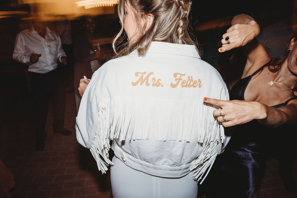 bride wearing wedding jacket that says mrs felter
