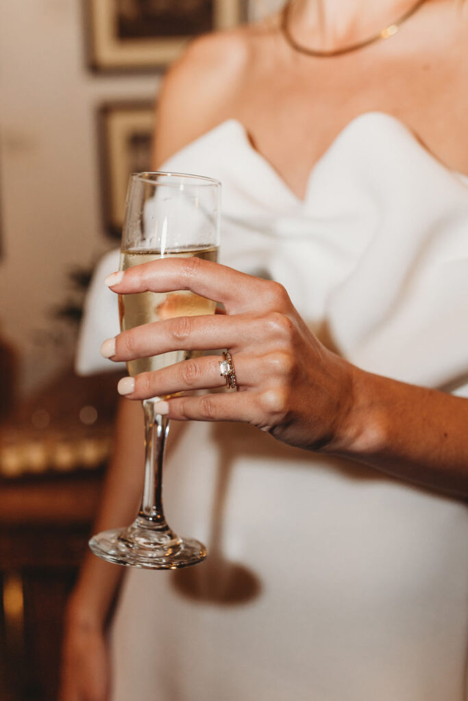 Bride holding champagne glass with wedding ring