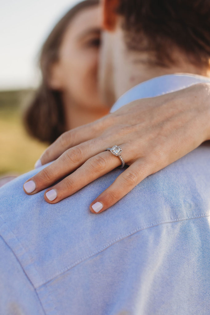 Women with hands wrapped around fiances back during engagement session