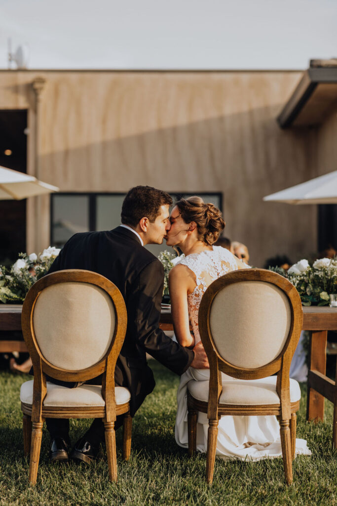 bride and groom kissing at sweethearts table